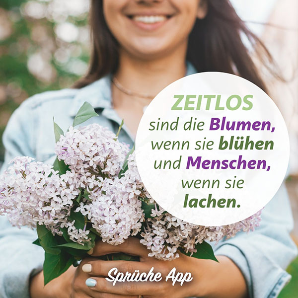 Lächelnde Frau hält einen Strauß Flieder, mit dem Spruch: „Zeitlos sind die Blumen, wenn sie blühen und Menschen, wenn sie lachen."